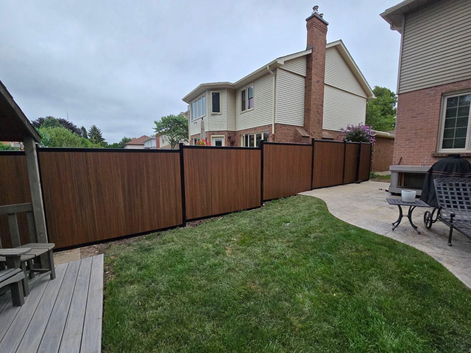 Dark woodgrain vinyl privacy fence with black posts